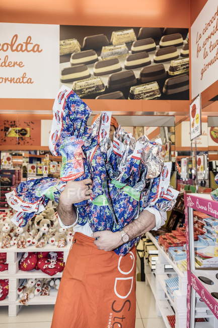 13. april 2017. italien, milan. Mann trägt Berge von Süßigkeiten im Geschäft — Stockfoto