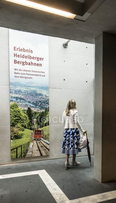 2. august 2016. deutschland, heidelberg. Hinteres Porträt einer Frau, die mit Regenschirm in der Nähe von Plakaten läuft — Stockfoto
