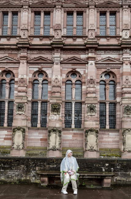 2 agosto 2016. Heidelberg. Ritratto di donna matura in tuta da pioggia seduta sulla panchina vicino al castello — Foto stock