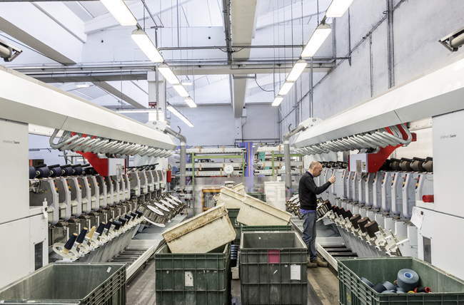 1 marzo 2017. Italia, Valle Mosso, Biella, Reda 1865 fabbrica tessile. Uomo che lavora su macchinari di produzione — Foto stock