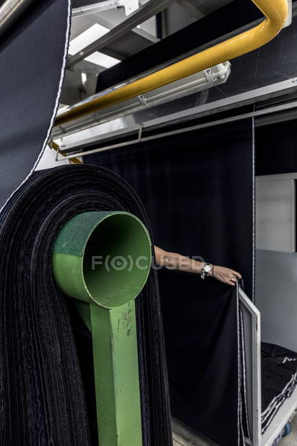 Cropped view of hand fitting fabric on production line — Stock Photo
