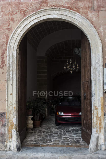 Апулия, Галлиполи. Красная машина и велосипед припаркованы в арочном доме — стоковое фото