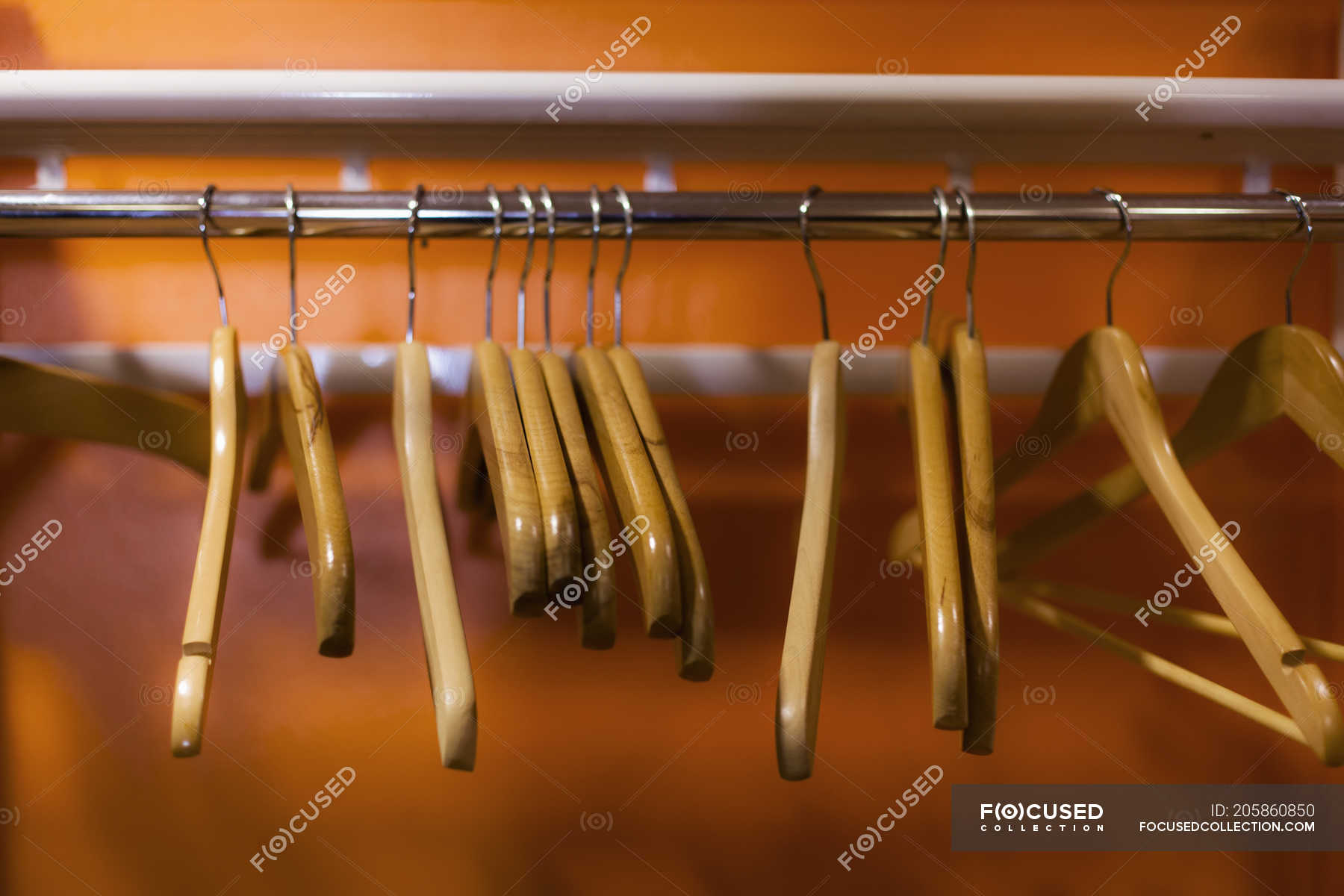 Wooden Coat Hangers Hanging On Clothes Rack In Cabinet