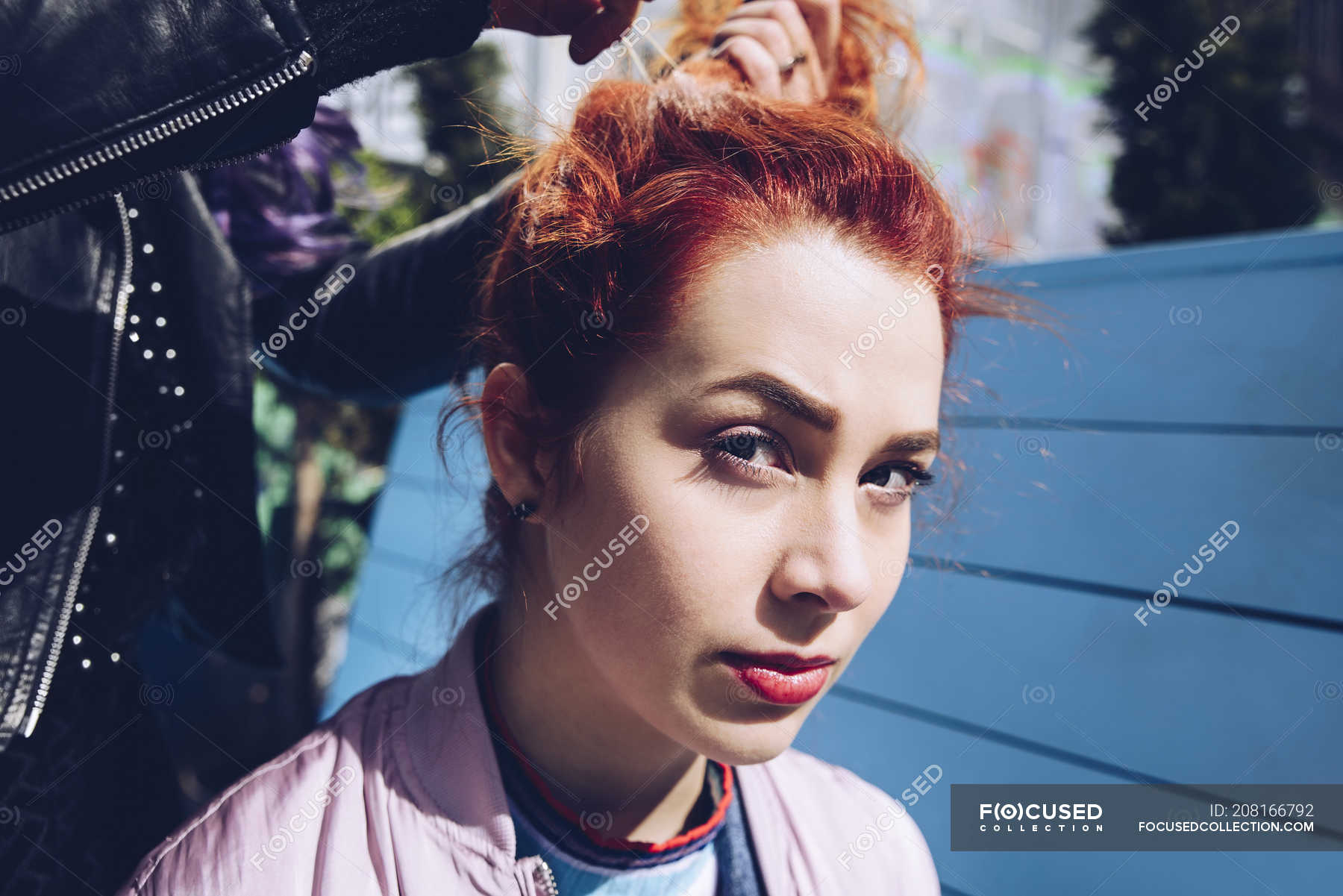 Portrait Of Redhead Woman With Friend Tying Hair Looking At