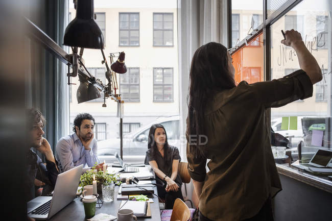 Creative Business People Looking At Female Coworker Writing