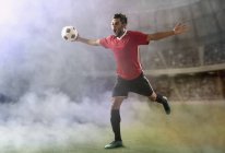 Futebolista comemorando gol, correndo através do campo de futebol na fumaça — Fotografia de Stock