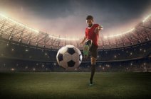 Joueur de football donnant un coup de pied au ballon — Photo de stock