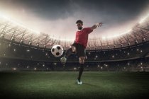 Jogador de futebol chutando bola no estádio — Fotografia de Stock