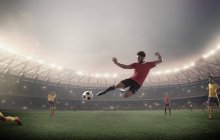 Un footballeur donne un coup de pied devant les projecteurs — Photo de stock