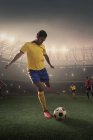 Футболист пинает мяч на стадионе — стоковое фото