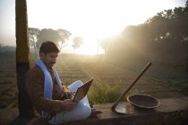 Agricultor sentado perto do campo agrícola e usando computador portátil — Fotografia de Stock