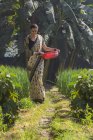 Индийская женщина ходит по полю сельского хозяйства с пластиковой кастрюлей в руке — стоковое фото