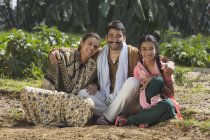 Famiglia indiana sorridente seduta sul campo agricolo — Foto stock