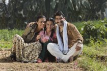 Усміхаючись індійській сім'ї, сидячи на сільському господарстві, сфері — стокове фото