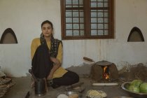 Индийская женщина сидит на кухне на полу — стоковое фото