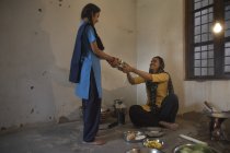 India mujer cocinar comida y dando tiffin caja a hija - foto de stock