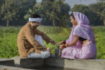 Couple indien assis près du réservoir d'eau dans le domaine de l'agriculture — Photo de stock