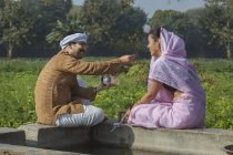 Indisches Paar sitzt in der Nähe eines Wassertanks in einem landwirtschaftlichen Feld — Stockfoto