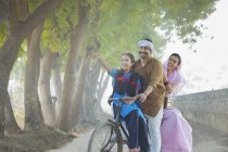 Feliz pareja rural junto con su hija montar en bicicleta en el pueblo - foto de stock