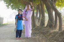 Индийская женщина ходит с дочерью по проселочной дороге — стоковое фото