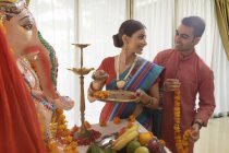 Індійський чоловік і жінка в святковий одяг поблизу релігійних статуя дивляться один на одного — стокове фото