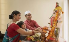 Familia en ropa festiva realizando aarti en Ganesh chaturthi - foto de stock