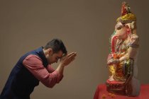 Man praying with hands joined and eyes closed in front of Ganpati Idol — Stock Photo