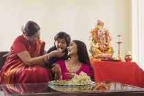Famille indienne en vêtements de fête et nourriture traditionnelle sur table en verre — Photo de stock