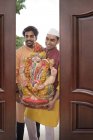 Dos hombres indios en ropa festiva con estatua religiosa en las manos - foto de stock