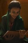 Retrato de chica india mirando almohadilla de examen bajo la luz de fondo - foto de stock
