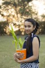 Visão de ângulo baixo de sorrir jovem segurando vaso de flores na mão no parque — Fotografia de Stock