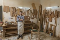 Porträt eines Zimmermanns, der in seiner Werkstatt steht und einen Hammer mit verschränkten Armen hält — Stockfoto