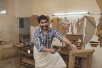 Carpintero sonriente trabajando con martillo en taller - foto de stock