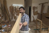 Плотник мужчина проверяет прямоту деревянного бревна в мастерской — стоковое фото