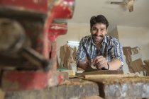 Low angle view of Smiling carpenter working in workshop — Stock Photo