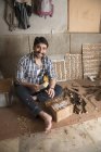 Carpenter making carvings and designs on wood using chisel in workshop — Stock Photo