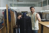 Tailleur debout à côté du mannequin portant un manteau semi-cousu en atelier — Photo de stock