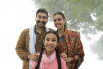 Портрет улыбающейся индийской семьи, смотрящей в камеру на улице — стоковое фото