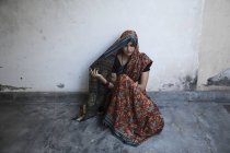 Visão de alto ângulo da mulher sentada no chão e cobrindo a cabeça com sari — Fotografia de Stock