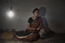 Donna indiana seduta sul pavimento in una stanza poco illuminata — Foto stock