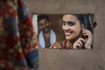 Lächelnde Frau, die in den Spiegel schaut und Ohrringe mit — Stockfoto
