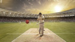 Joven deportista golpeando pelota mientras batea en el campo de cricket - foto de stock