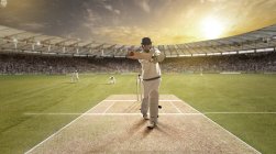Young sportsman striking ball while batting at cricket field — Stock Photo