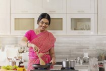 Женщина в сари приготовления пищи на кухне — стоковое фото