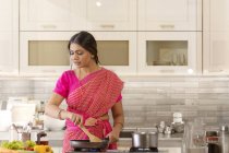 Woman in saree cooking in the kitchen — Stock Photo