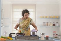 Mujer preparando comida en la cocina - foto de stock