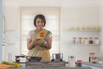 Mujer sosteniendo plato dulce en la cocina - foto de stock