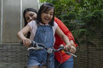 Mother helping daughter riding cycle — Stock Photo