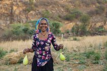 Женщина держит бутылку тыквы и улыбается, в поле — стоковое фото