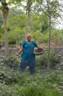 Frau streut Dünger auf ihre Pflanzen — Stockfoto